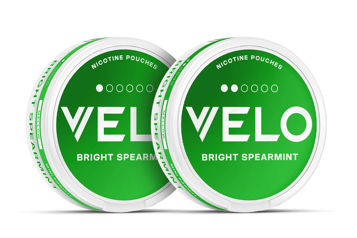 Velo Nicotine Pouches |  Two round, green cans of Velo Bright Spearmint nicotine pouches are placed side by side. Both display the Velo brand name and Nicotine Pouches text on their lids.
