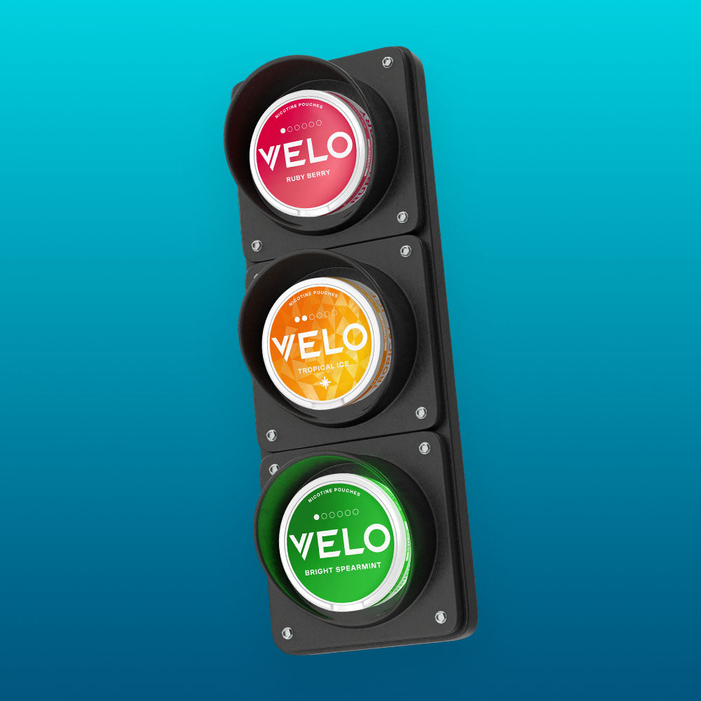 Velo Nicotine Pouches |  A traffic light with red, yellow, and green lights replaced by round Velo nicotine pouches labeled Ruby Berry, Tropical Gel, and Bright Spearmint, against a blue gradient background.