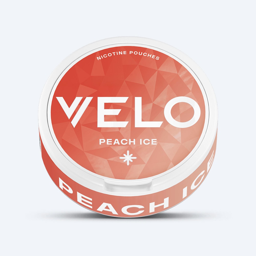 Velo Nicotine Pouches |  A round container of VELO Peach Ice nicotine pouches sits on a white background. The lid displays an orange geometric pattern, the VELO brand name in large white text, and a small asterisk icon, suggesting a cool and refreshing flavor. The side of the container is clearly labeled with "PEACH ICE.
