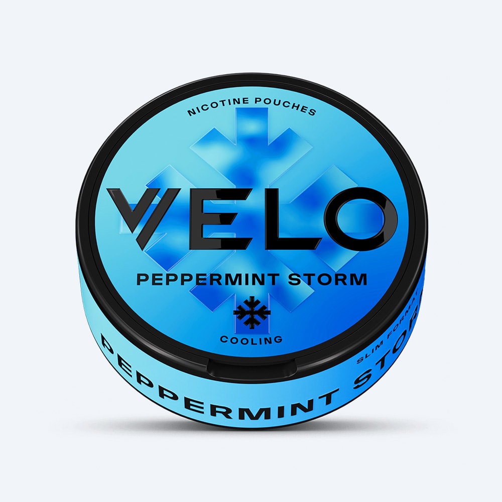 Velo Nicotine Pouches |  A round blue can labeled "VELO Peppermint Storm," featuring a snowflake design and text highlighting nicotine pouches with a refreshing peppermint cooling sensation.