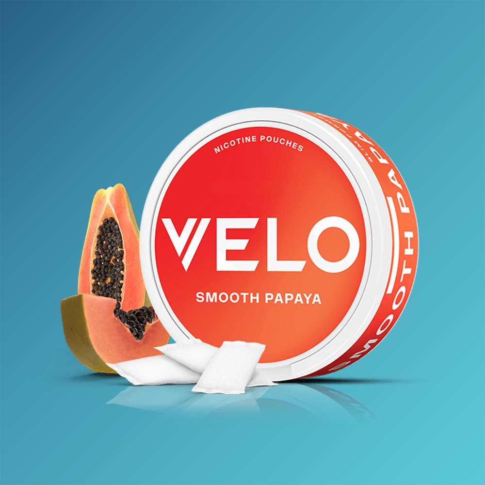 Velo Nicotine Pouches |  A can of VELO Smooth Papaya is displayed with two nicotine pouches placed in front and a sliced papaya beside it, all set against a blue background that highlights the tropical essence of the product's flavour.