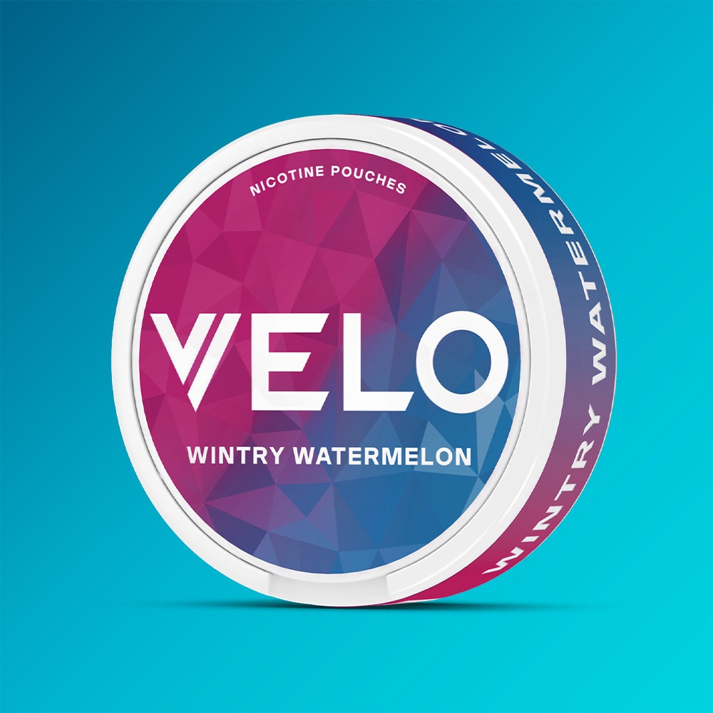 Velo Nicotine Pouches |  A round tin of VELO's Wintry Watermelon nicotine pouches, with a refreshing peppermint twist and a blue-and-pink geometric lid design, displayed against a gradient blue background.