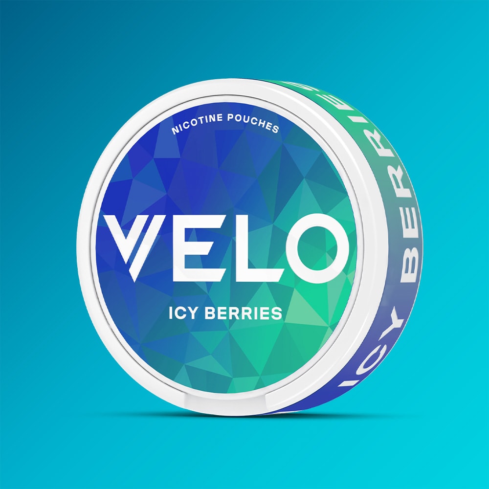 Velo Nicotine Pouches |  A round tin labeled VELO Icy Berries nicotine pouches, adorned with a blue and green geometric design, rests against a blue gradient background. This product offers a minty cool sensation with each pouch, combining an energizing triple-berry blend and an invigorating cooling effect.