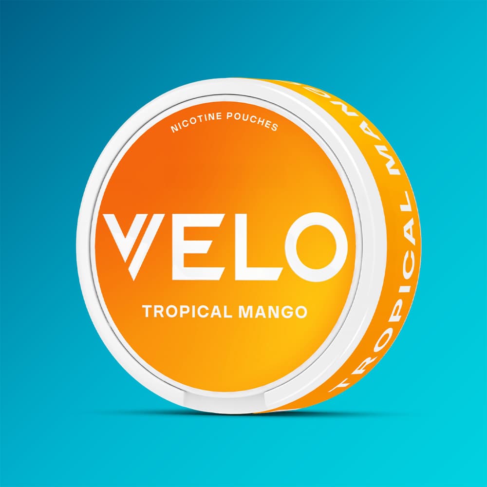 Velo Nicotine Pouches |  A round container of VELO Tropical Mango, featuring an orange and white design, is set against a blue gradient background to emphasize the exotic fruit flavours that make this VELO variety a refreshing choice.