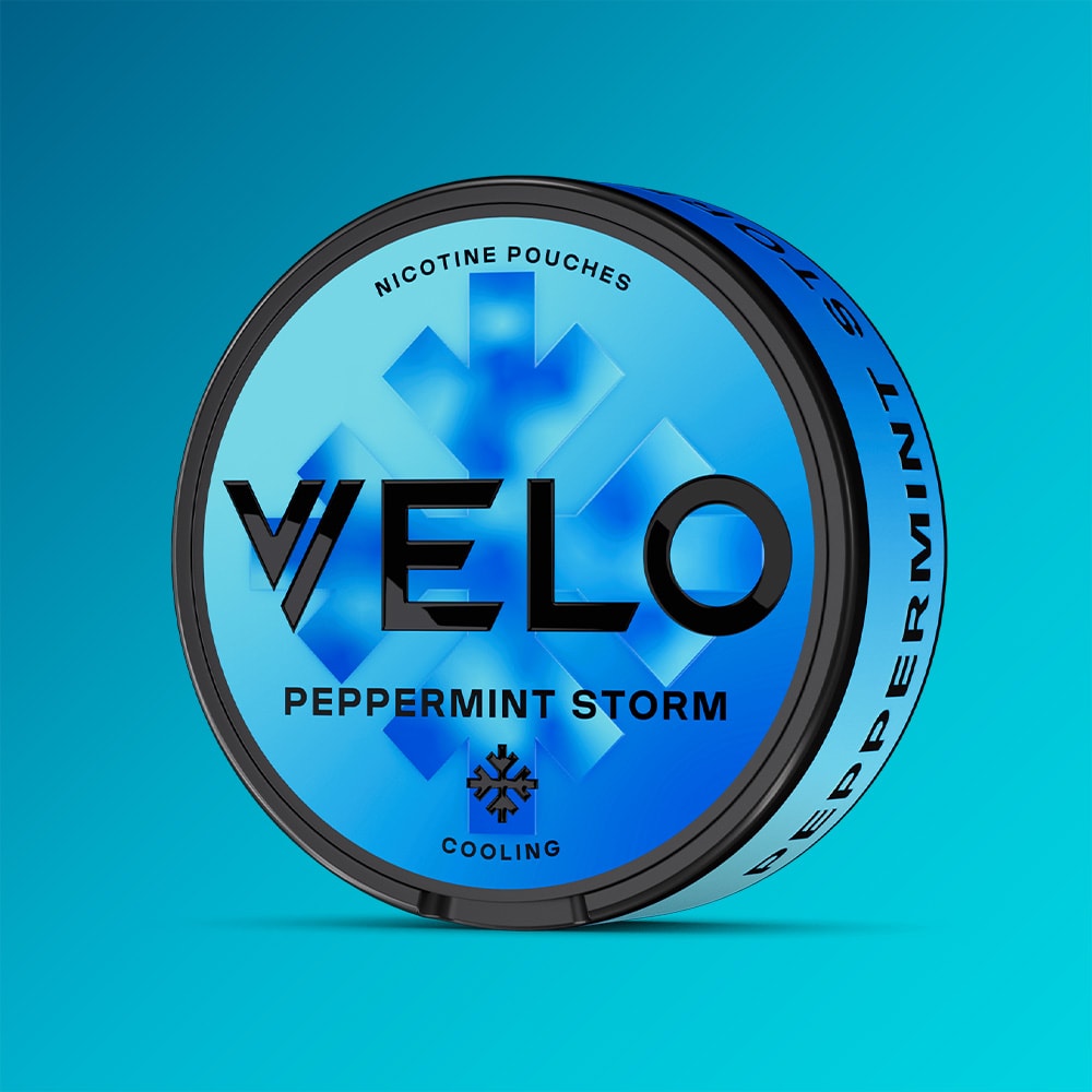 Velo Nicotine Pouches |  A round blue can labeled "VELO Peppermint Storm" is displayed against a blue gradient background, emphasizing its refreshing peppermint flavor and invigorating cooling sensation with “Nicotine Pouches” and “Cooling” printed on the packaging.