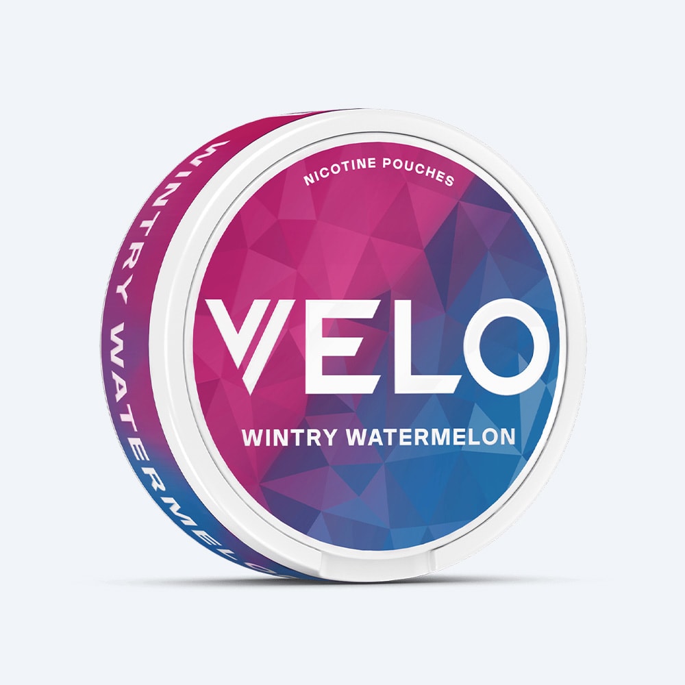 Velo Nicotine Pouches |  The VELO Wintry Watermelon nicotine pouch comes in a round container featuring a bold geometric blue and pink design with striking white text on the lid and side. This refreshing flavor combines juicy watermelon notes with a cool hint of peppermint.
