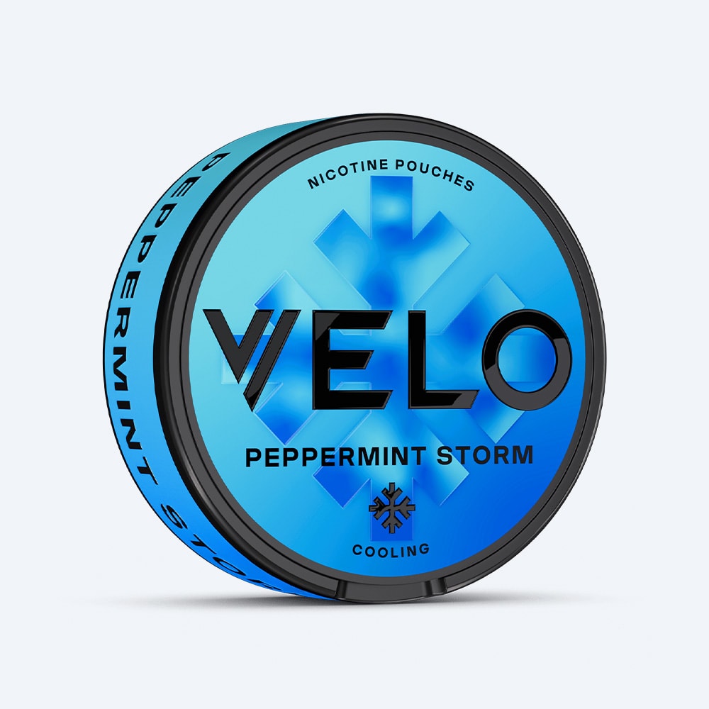 Velo Nicotine Pouches |  A blue, round container of VELO Peppermint Storm nicotine pouches—featuring a snowflake motif and the words "Peppermint Storm" and "Cooling" on the front—offers a refreshing peppermint flavor with an intense menthol-like cooling sensation.