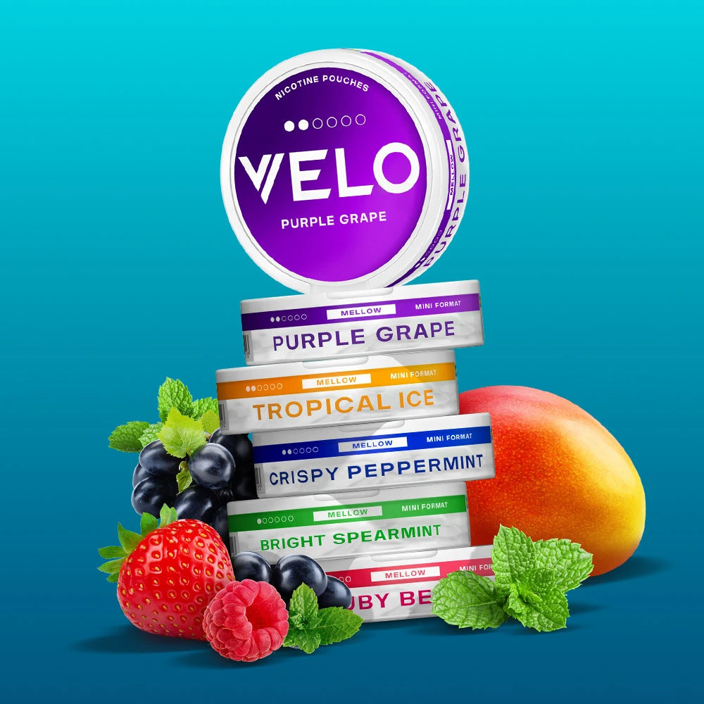 Velo Nicotine Pouches |  A stack of Velo nicotine pouch containers in various flavors, with fruit like grapes, mango, raspberry, and mint leaves around them, set against a blue gradient background. These sleek pouches offer a refreshing way to enjoy nicotine on the go.