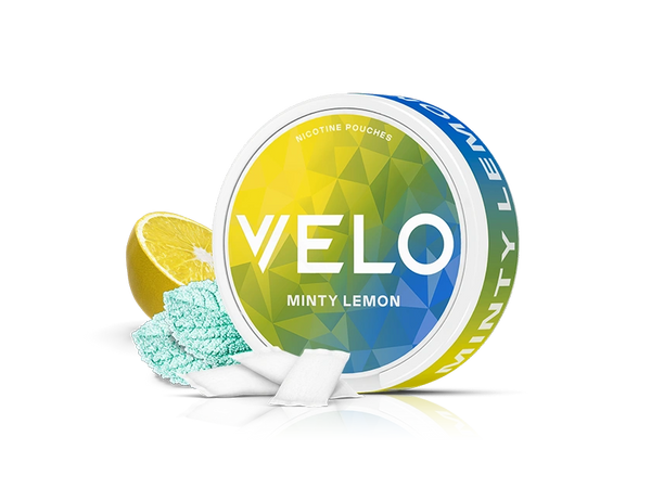 Velo Nicotine Pouches |  A round container of VELO Minty Lemon nicotine pouches is shown with a sliced lemon, blue mint powder, and several white rectangular Velo pouches in front. The background is plain white.