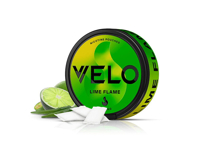 Velo Nicotine Pouches |  Round VELO Lime Flame nicotine pouches container, green and yellow with black text, is shown alongside a sliced lime, green chili, and two white nicotine pouches on a white background.