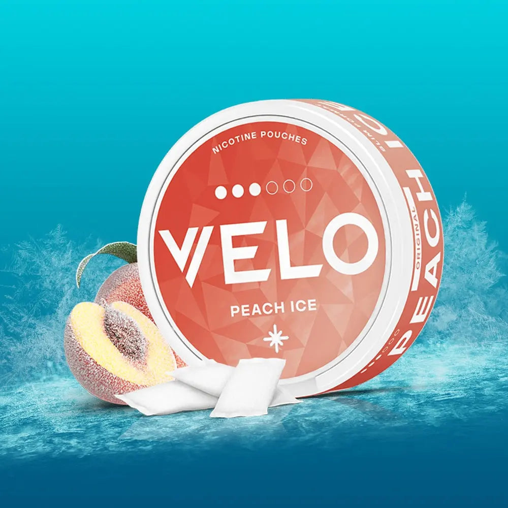 Velo Nicotine Pouches |  A round container of VELO Peach Ice nicotine pouches sits on ice, with a fresh peach and several Velo pouches arranged beside it. The background features a gradient blue, enhancing the cold, frosty effect and highlighting the cool sensation of these nicotine pouches.